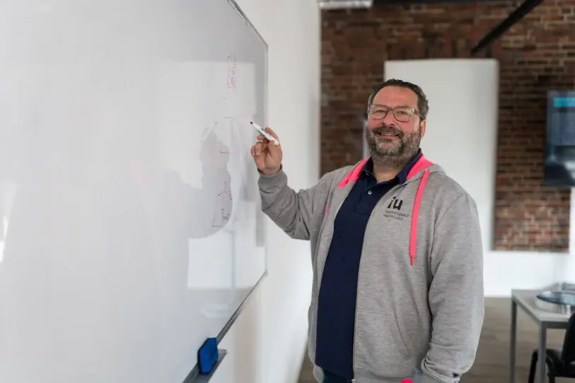 Professor Hoodie teaching whiteboard smiling