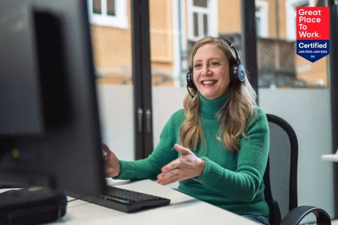 Frau im Sales sitzt am Laptop und Great Place to Work Logo