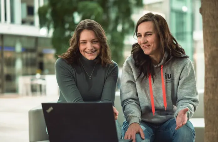 Christina zeigt dualer Studentin etwas am Laptop Campus München
