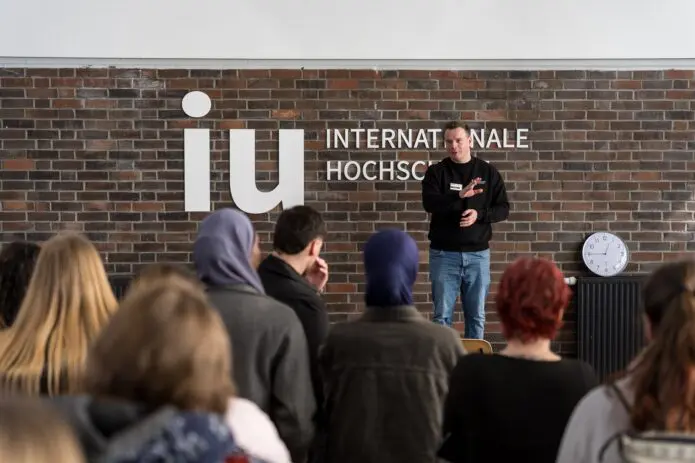 Man helds presentation in front of students IU logo in the background
