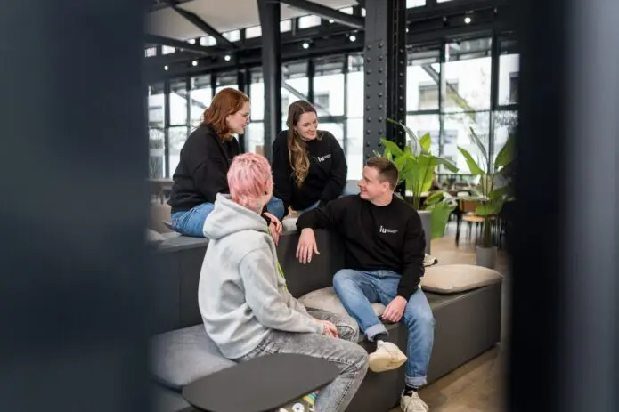 four people sitting at stairs Campus vibe smiling