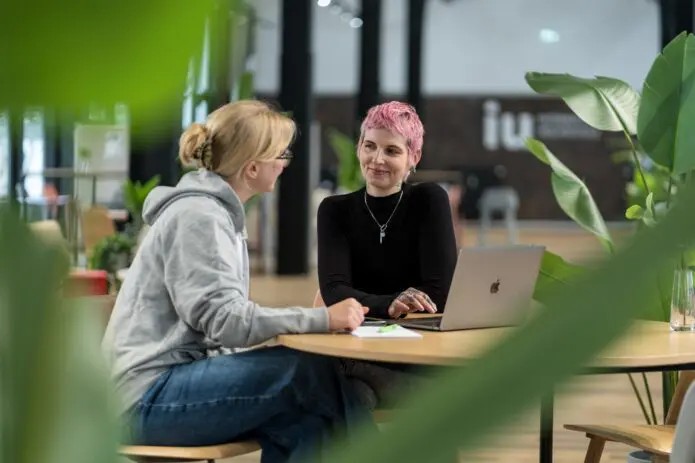 two women speaking table Campus