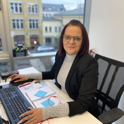 Bettina, unsere Standortleitung zeigt sich an ihrem Arbeitsplatz, im Büro der IU.