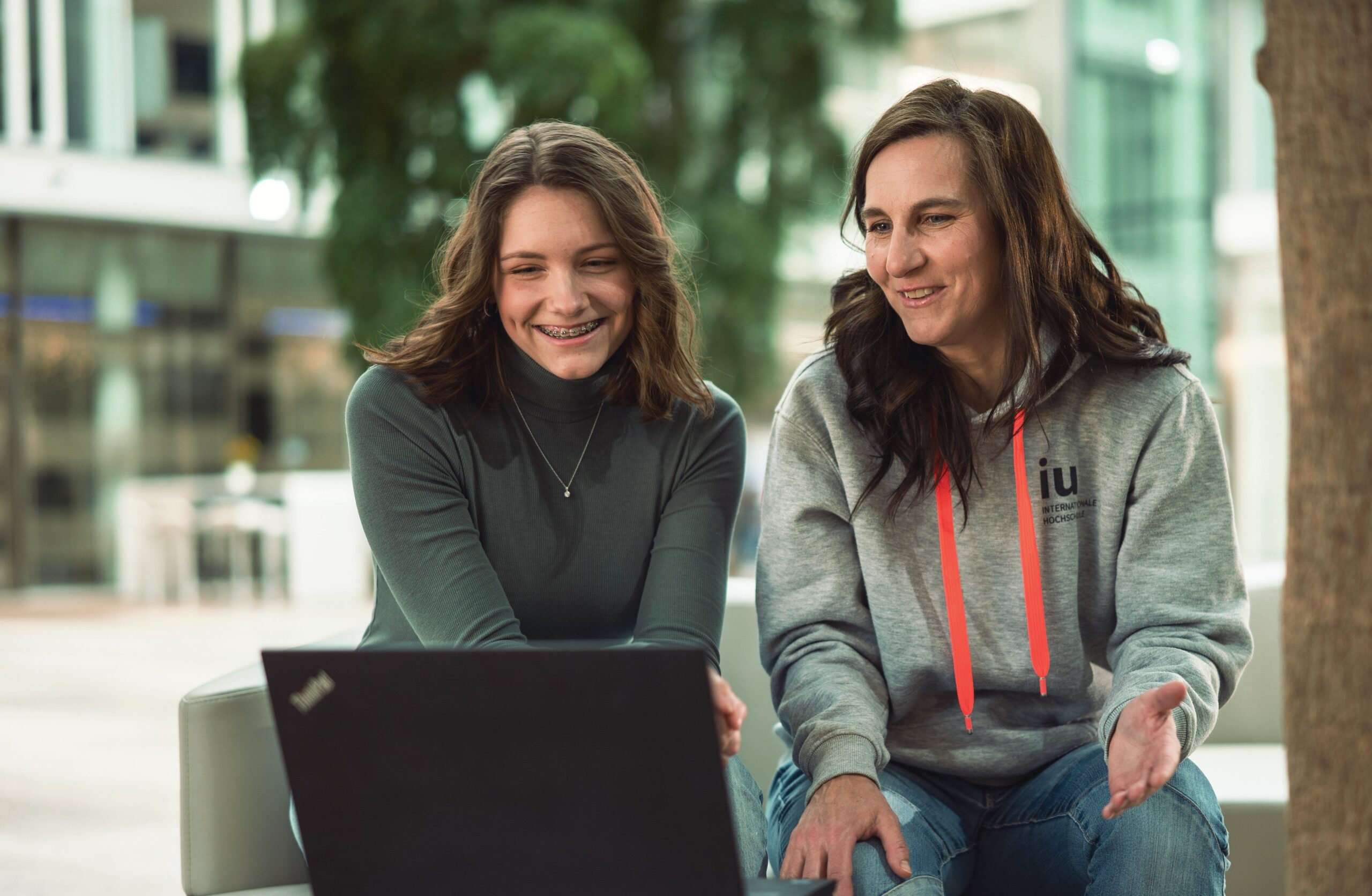 Christina zeigt dualer Studentin etwas am Laptop Campus München