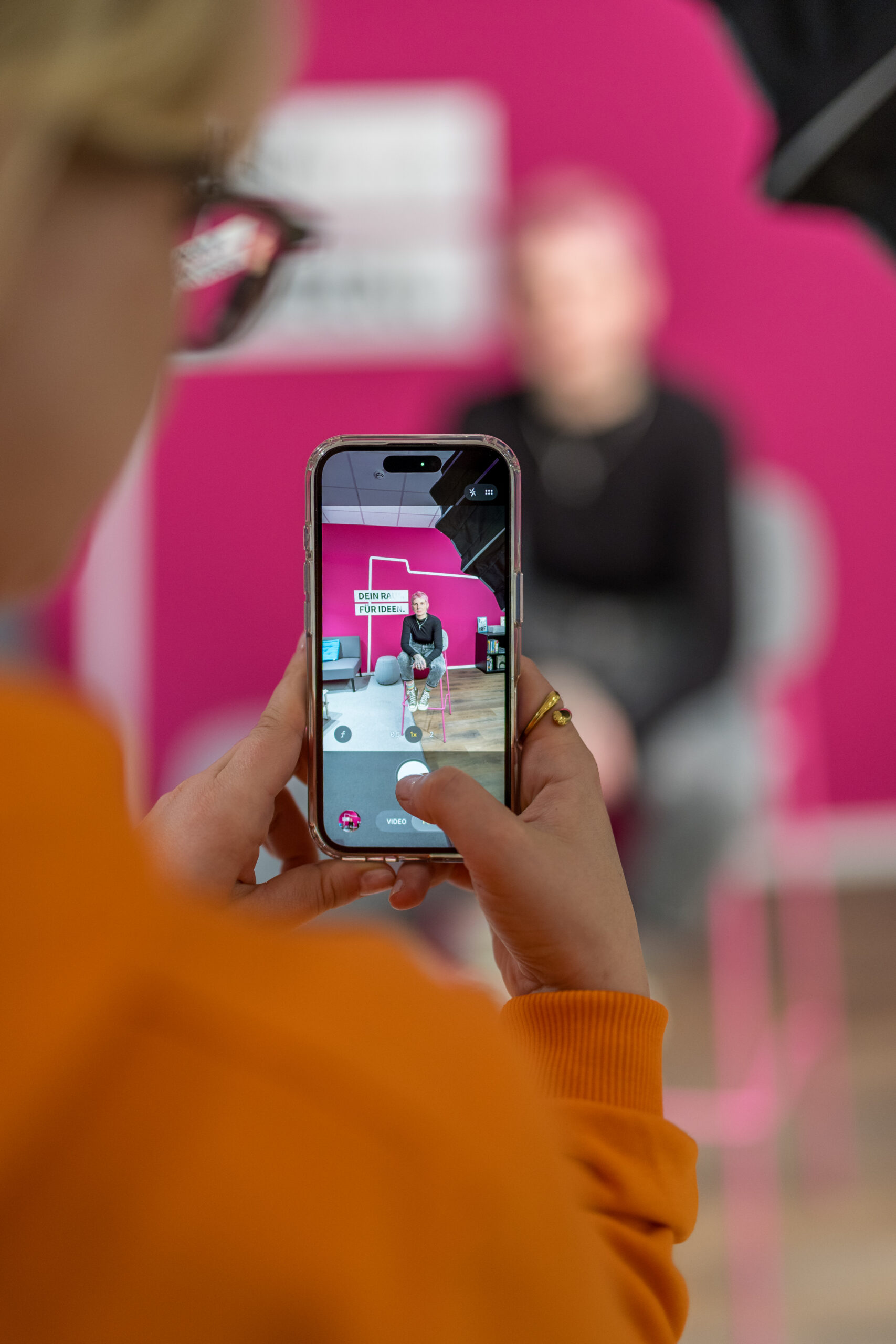 Woman helds Iphone taking picture of colleague
