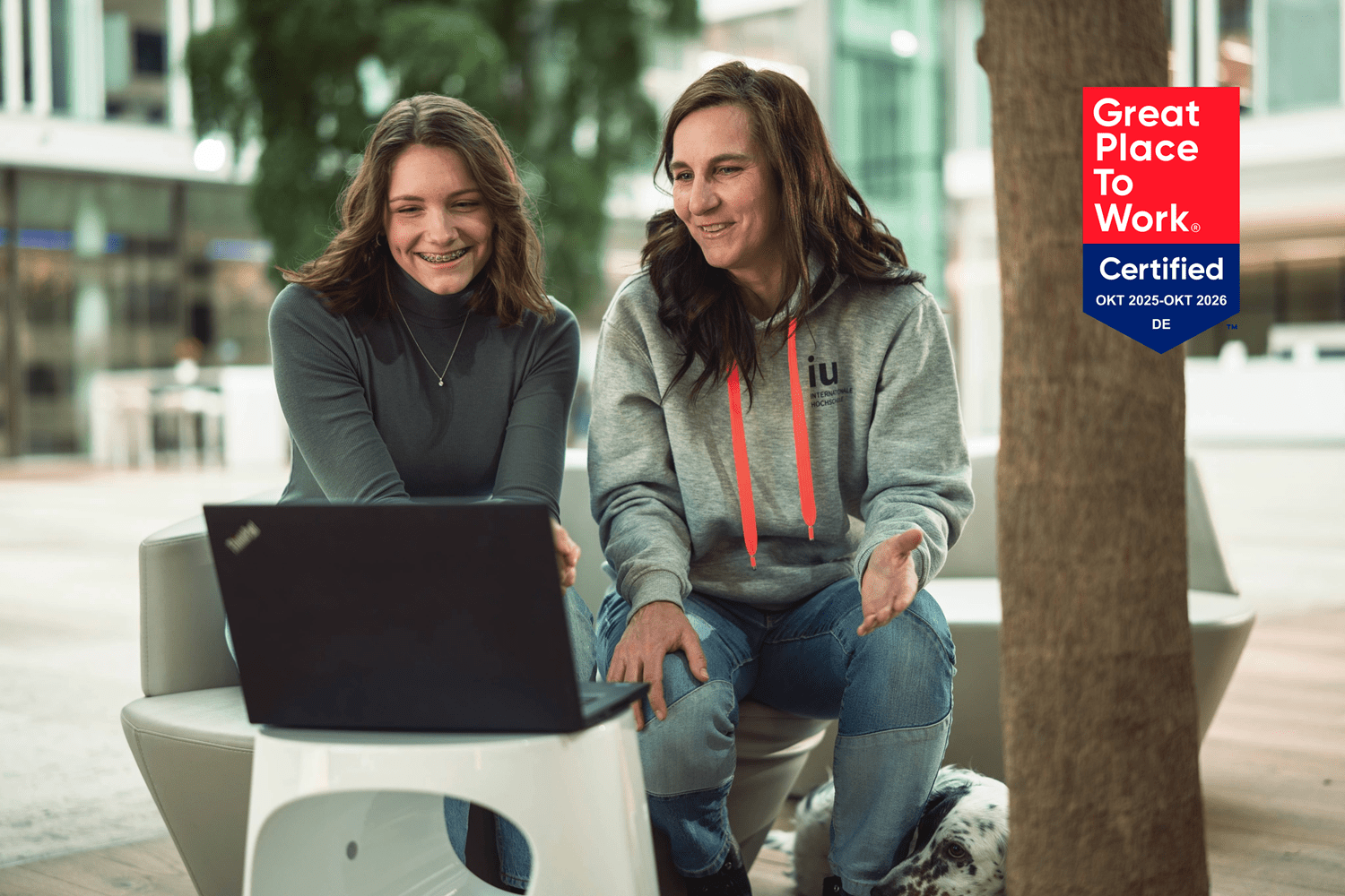 Studienberaterin und Studentin vor Laptop sitzend im Gespräch, Kulisse ist modernes Büro